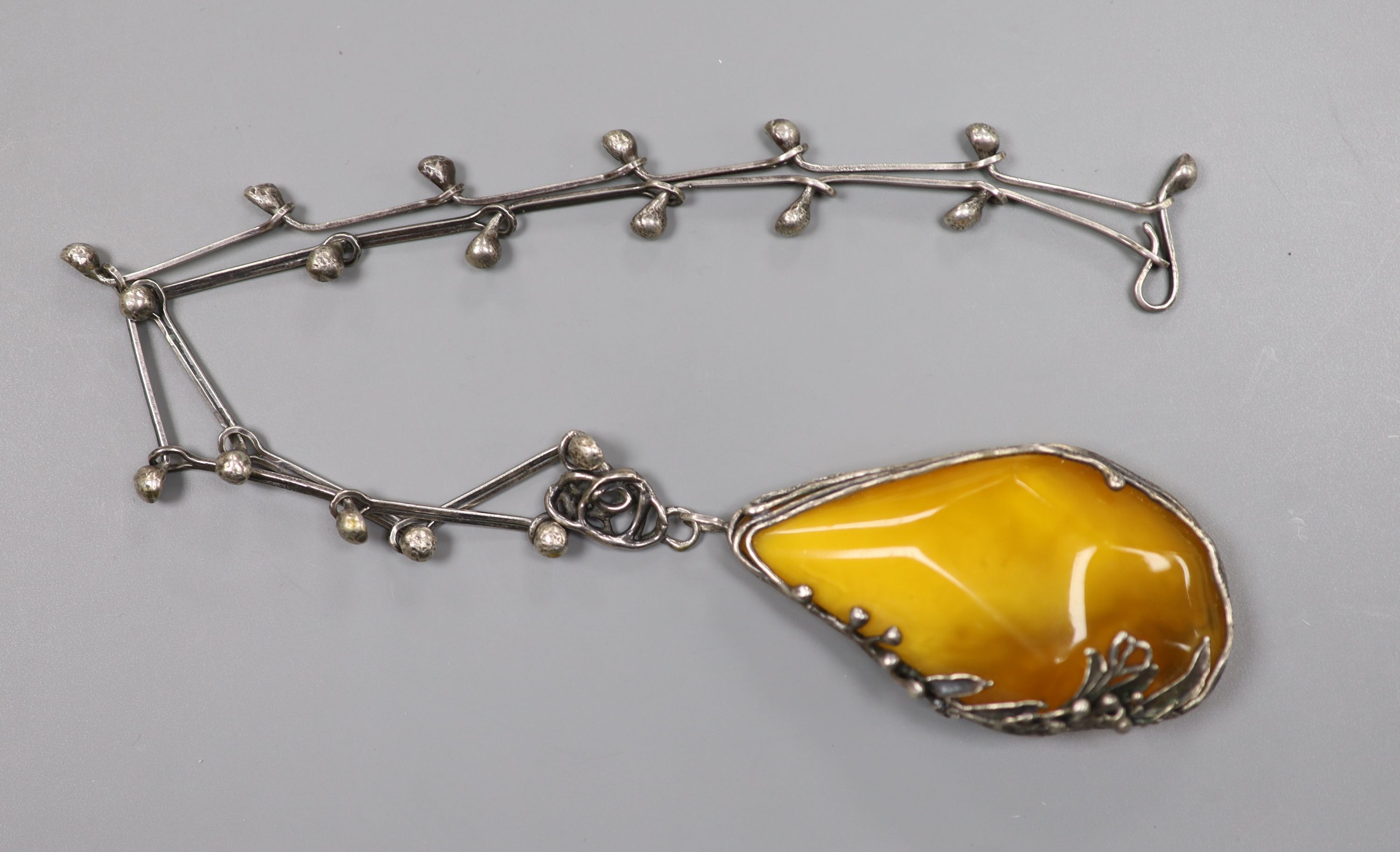 A stylish white metal and amber pebble set pendant necklace